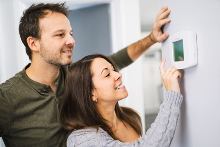 couple adjusting thermostat